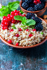 Quinoa salad with berries, mint and walnuts on a dark wooden background. Superfoods  clean eating concept.