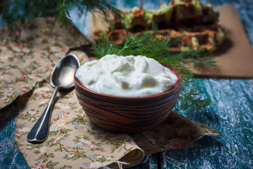 Homemade yogurt in a rustic bowl, herbs on an old wooden table