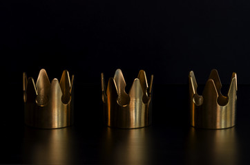 Three gold crowns on black background for Tres Reyes Magos  or Three Wise Men concept background.