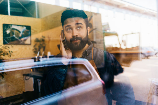 A coffee roaster talking on a cell phone and looking through a window in Sweden