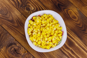 Canned sweet corn in a bowl on wooden table