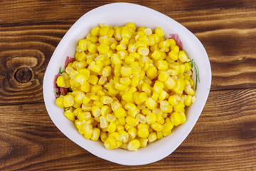 Canned sweet corn in a bowl on wooden table