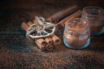 Cinnamon sticks and  powder close up on wooden background, rustic style