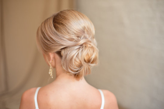Rear view of female hairstyle middle bun with blond hair.