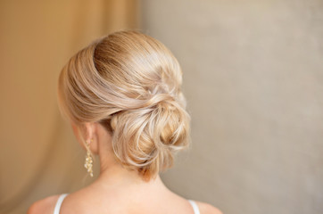 Rear view of female hairstyle middle bun with blond hair.
