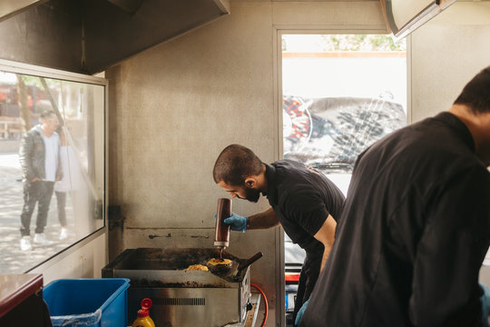 Chef cooking burgers on the grill in a food truck