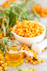 Natural, organic sea-buckthorn berry in bowl and and sea buckthorn oil in glass vintage bottle