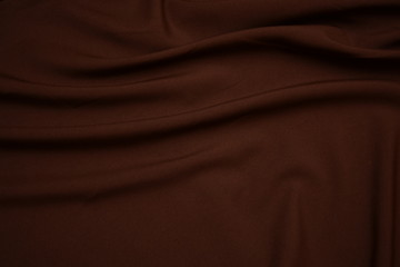 Texture of dark brown fabric closeup. Low key photo. Plexus threads. Clothing industry. Abstract background. Textile waves.