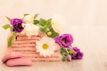 Stack of soft terry towels with flowers on wooden boards