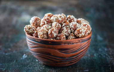 Sugared peanuts with sesame seeds on the wooden background