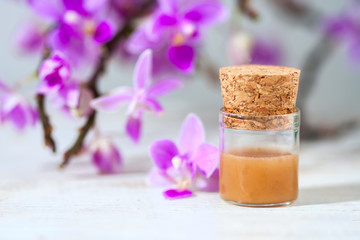 spa setting with cosmetic cream, gel and purple orchid on white wooden table background.