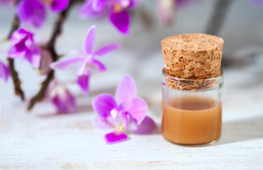 spa setting with cosmetic cream, gel and purple orchid on white wooden table background.