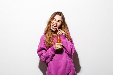 Portrait of optimistic woman 20s wearing sweatshirt drinking soda using straw, isolated over white background