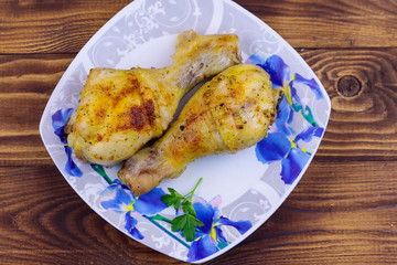 Baked chicken drumsticks with potatoes in a plate on wooden table