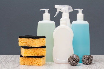 Bottles of dishwashing liquid and sponges on gray background.