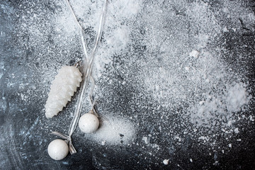 on a black snow-covered background lies white-silver baubles