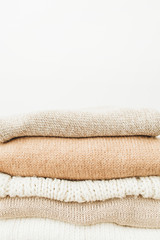 Fototapeta na wymiar Warm woolen sweaters and pullovers stack on white background. Woman fashion clothes on white background.