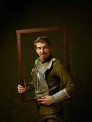 Medieval knight on dark studio background. Portrait in low key of brutal man in tradishional retro...