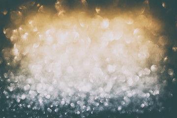 Defocused abstract silver and gold glitter with glowing sparks lights background. Holiday greeting card. Copy space. Diamond magic dust. Vignette