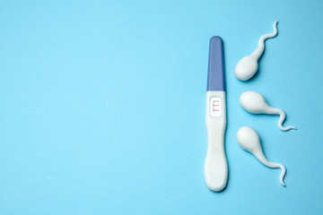 Positive pregnancy test with two stripes and sperm on blue background