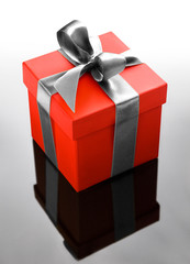 Single red gift box with silver ribbon on dark background.