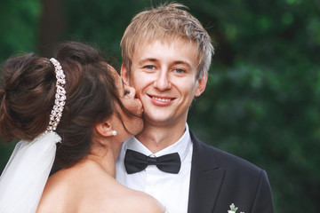 Lovely couple in love kissing each other on the day of the wedding they are even standing in the park