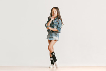 Full length portrait of cute little kid girl in stylish jeans clothes looking at camera and...