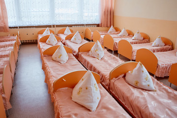 Beds and cots in brightly colored dormitory of a nursery.A lot of children's cots