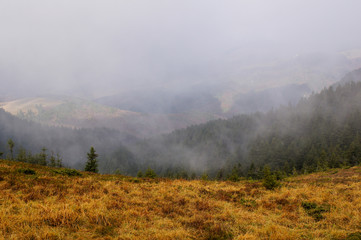 Obraz na płótnie Canvas Amazing landscape from Ciucas Peak in the Carpathian Mountains, Romania, on a hazy autumn day, when fog is lifting.