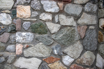 Wall of masonry stones of various colors close-up.