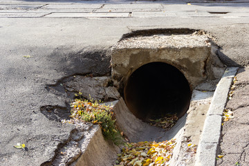 Exit of arge-diameter iron pipe ditch under the roadway to discharge rainwater flows in the city of...