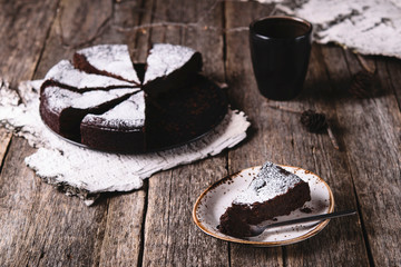 Kladdkaka. Traditional Swedish moist chocolate cake on old rustic wooden table decorated dry twigs, pine cones and birch bark. Fika. Hygge. Toned image - 236258612