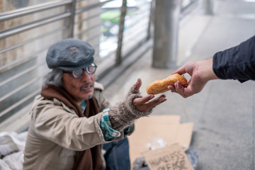 Old man homeless reach out to get bread from donor - obrazy, fototapety, plakaty