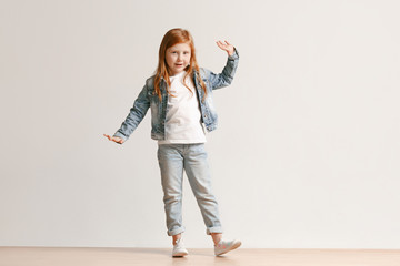Full length portrait of cute little kid girl in stylish jeans clothes looking at camera and...