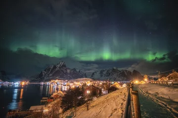 Photo sur Plexiglas Reinefjorden Aurora borealis over scandinavian village light shining in winter