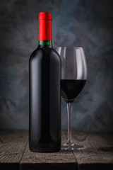 Bottle of red wine and glass close-up on wooden table