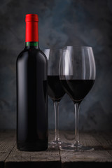 Bottle of red wine and two full glasses on a wooden table closeup
