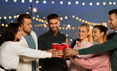 leisure, celebration and people concept - happy friends with drinks toasting at rooftop party at...