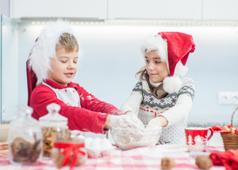 children in Christmas hats prepare cookies in the kitchen