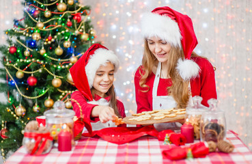 Merry Christmas and Happy Holidays. Mother and daughter bake cookies for Christmas