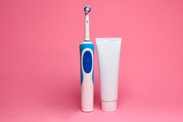 Modern electric toothbrush and spare heads on pink background