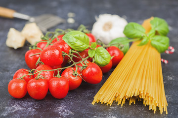Cherry tomatoes with spaghetti and garnish on dark background. Copy space horizontal.