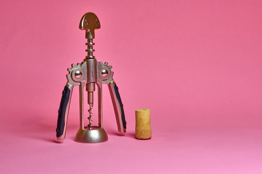 Corkscrew and cork on pink background. Party concept