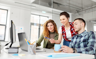 business, technology and people concept - happy creative team with laptop computer working at office