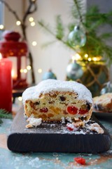 Dresden Christmas Stollen with raisins, dried apricots, dried cherries, nuts and candied fruits in sugar glaze on a festive background. Delicious festive Christmas dessert.