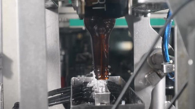 Automatic applying a bottle cap at the Beer Bottling Line. Beer manufacturing. Brewery concept. Technological line in beer factory. 4k