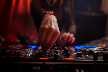 Blurred background with dj girl playing music and scratching tracks on professional dj midi controller.Modern disc jockey digital audio equipment for concerts or house party event.Stage lighting
