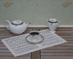English teacup with saucer, teapot and sugar bowl on a sheet of music