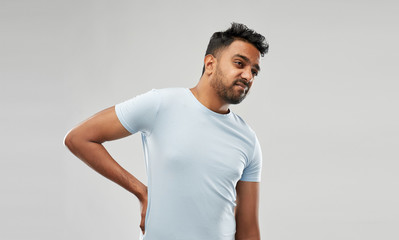 health problem and people concept - unhappy indian man suffering from pain in back or reins over...