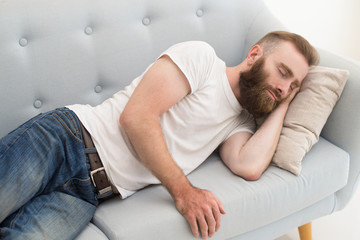 Bearded man lying and dosing on sofa. Handsome guy dozing. Relaxation concept.